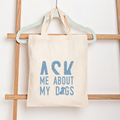 Tote bag with 'Ask Me About My Dogs' text on a wooden rack