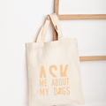 Beige tote bag with 'Ask Me About My Dogs' text on a white background