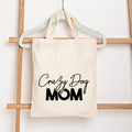 Tote bag with 'Crazy Dog Mom' text hanging on a wooden rack.