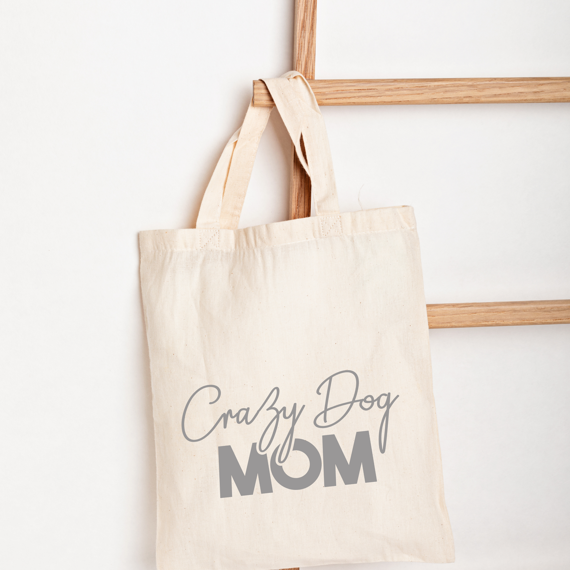 Beige tote bag with 'Crazy Dog Mom' text on a white background