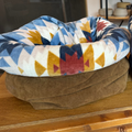 Dog bed with a colorful pattern on a wooden surface
