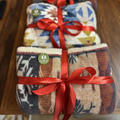 Two patterned blankets with red ribbons on a wooden surface