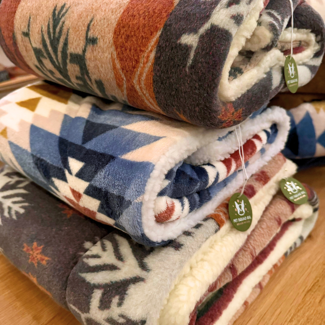 Stack of patterned blankets with tags on a wooden surface