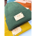 Green knit beanie with a brand label on a colorful background
