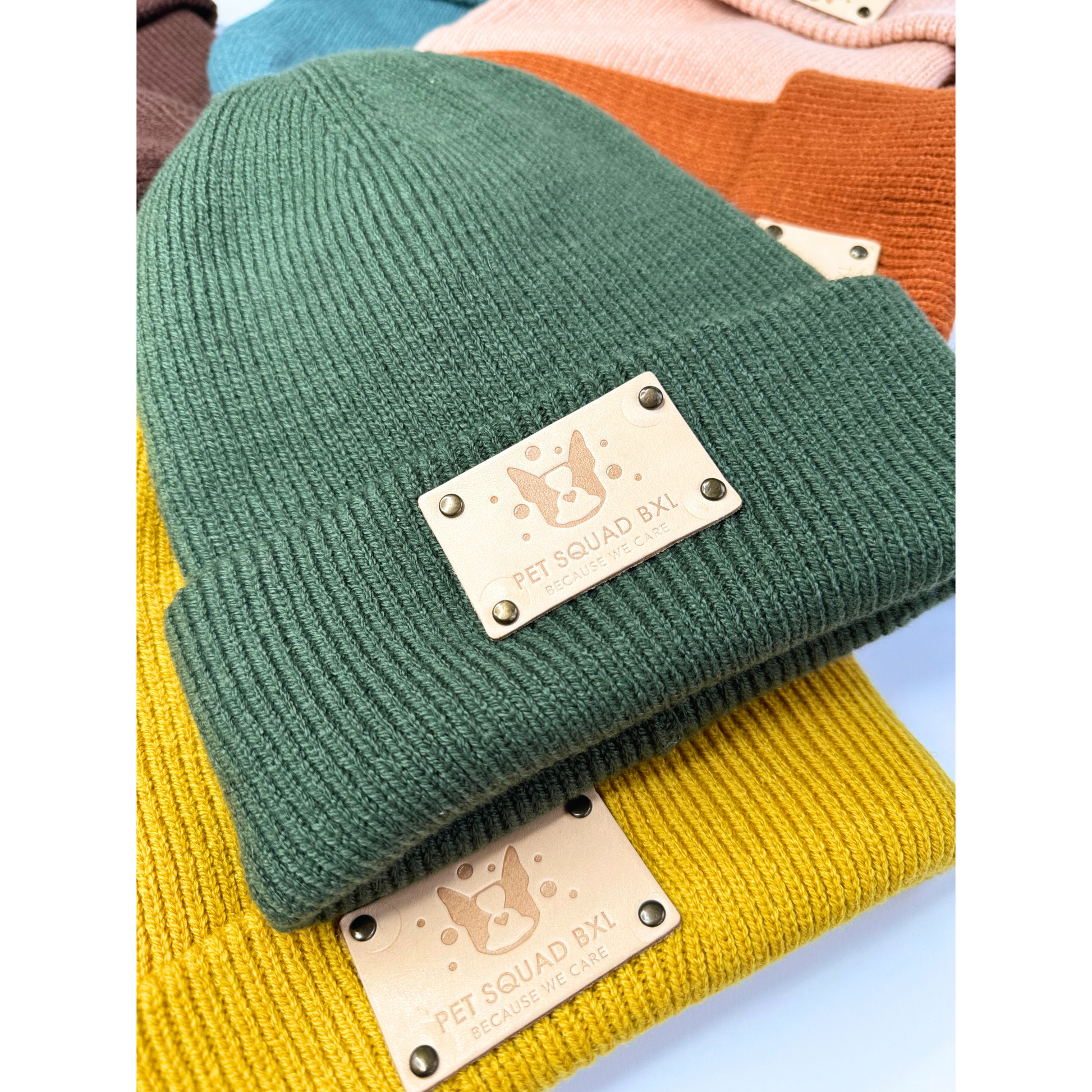 Green knit beanie with a brand label on a colorful background