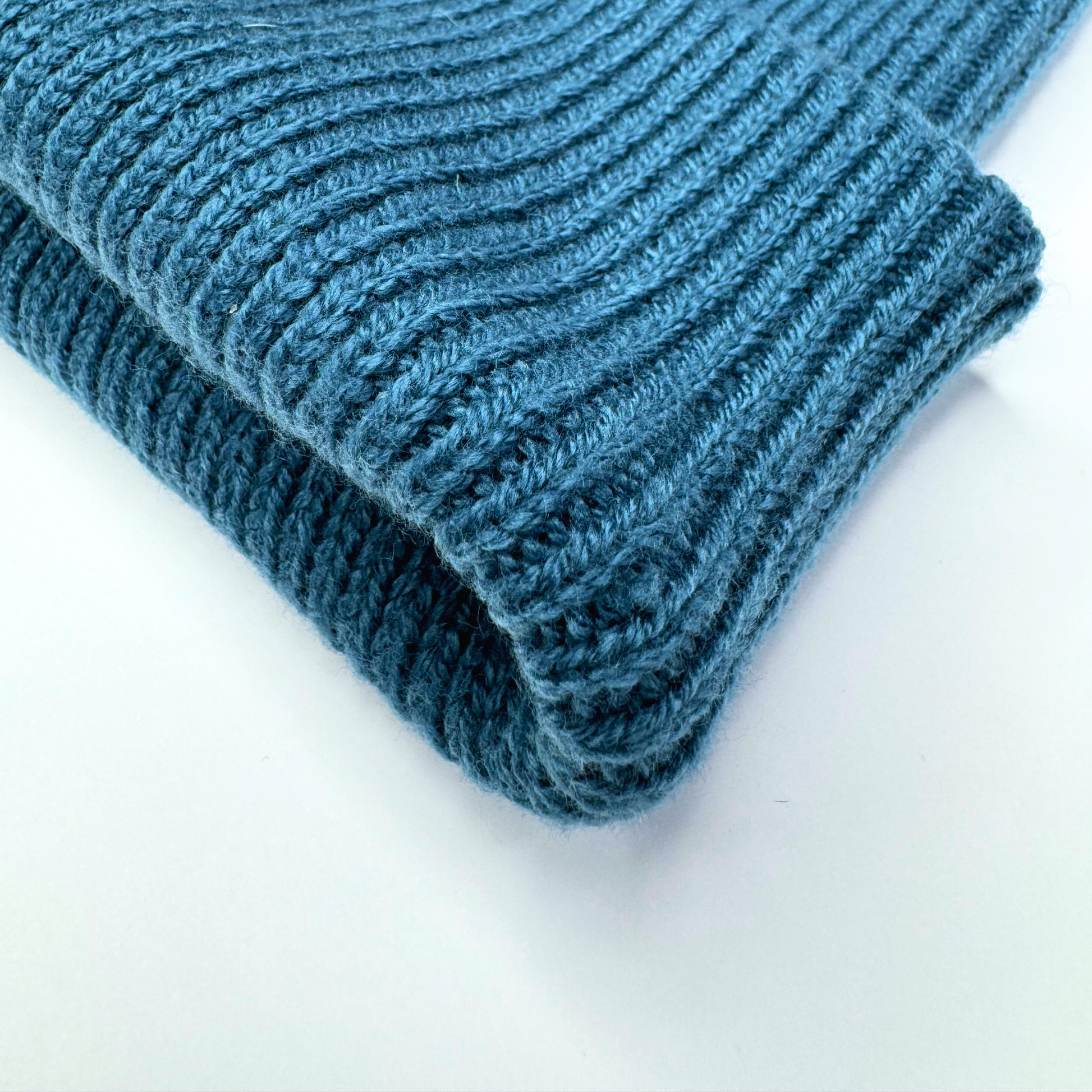 Folded blue knitted blanket on a white background