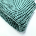 Folded teal knitted fabric on a white background