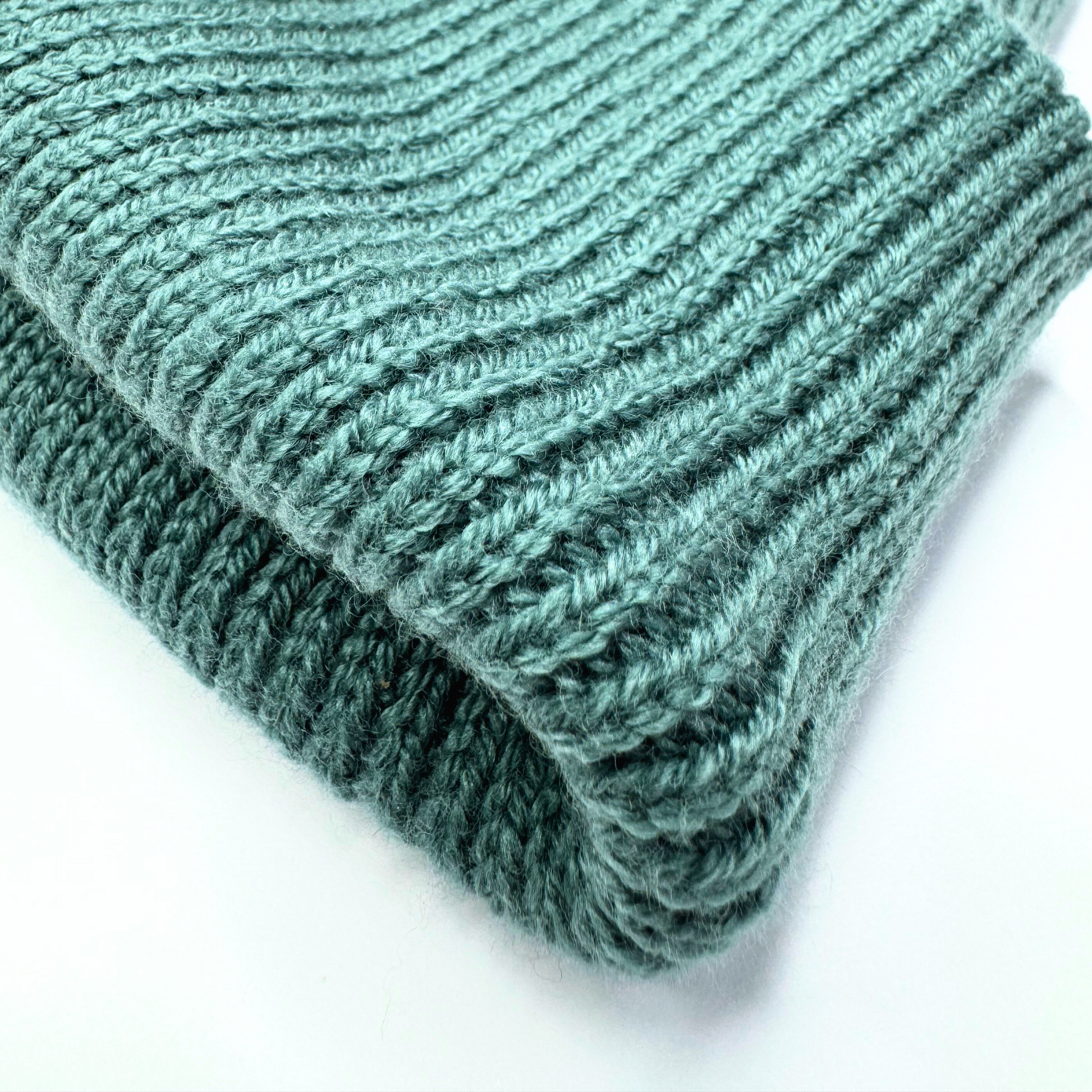 Folded teal knitted fabric on a white background