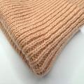 Close-up of a folded beige knitted fabric on a white background