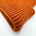 Stack of orange knitted fabric on a white background