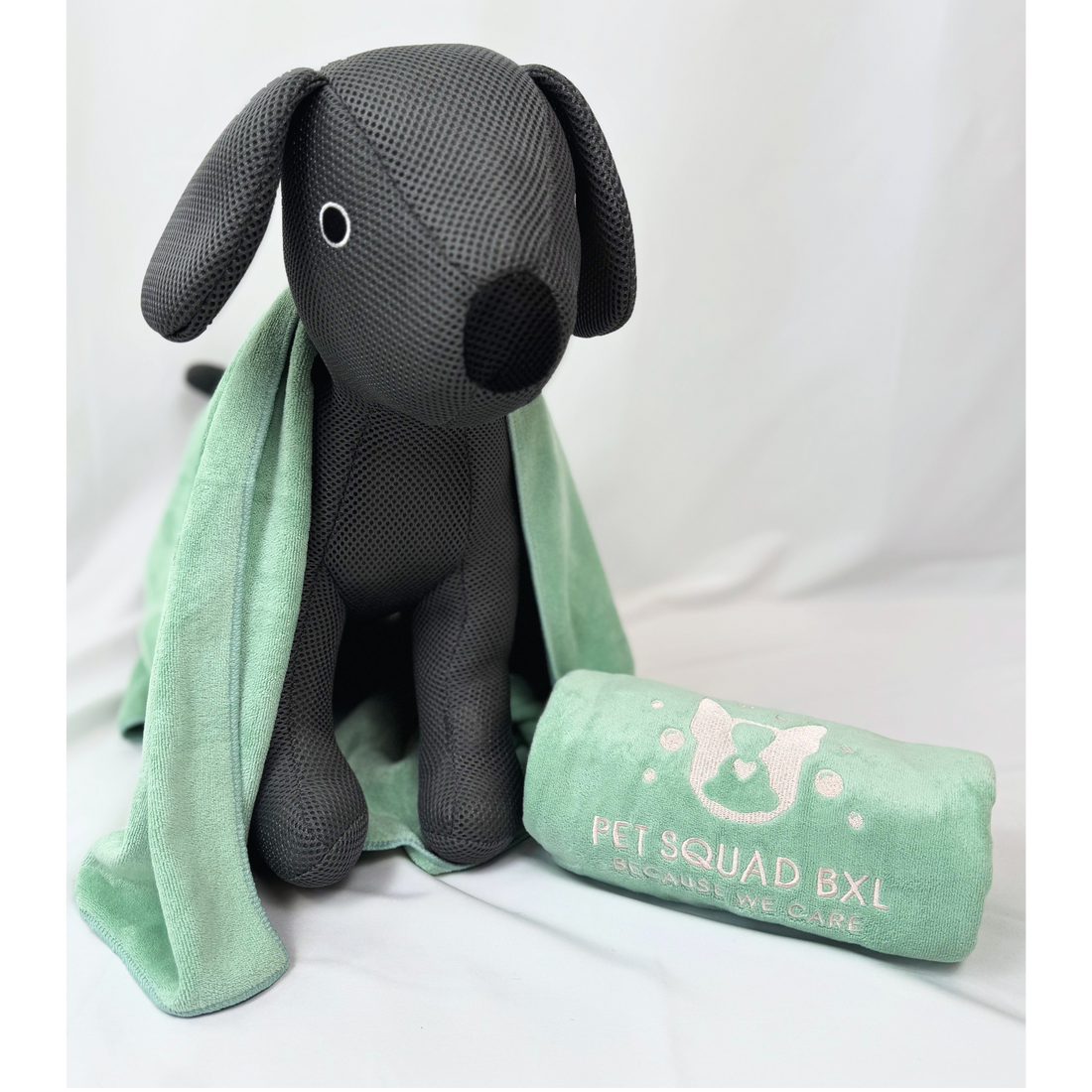 Black dog-shaped pillow with a green blanket and 'Pet Squad BXL' pillow on a white background