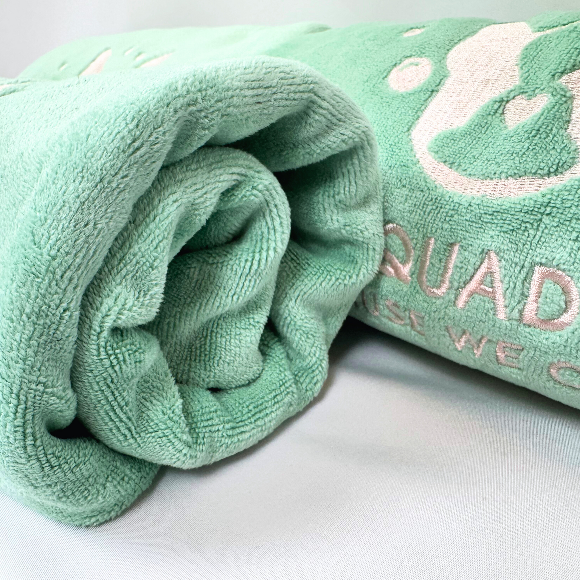 Folded green towel with 'Squad' text on a white background