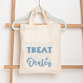 Tote bag with 'Treat Treat Dealer' text on a wooden rack
