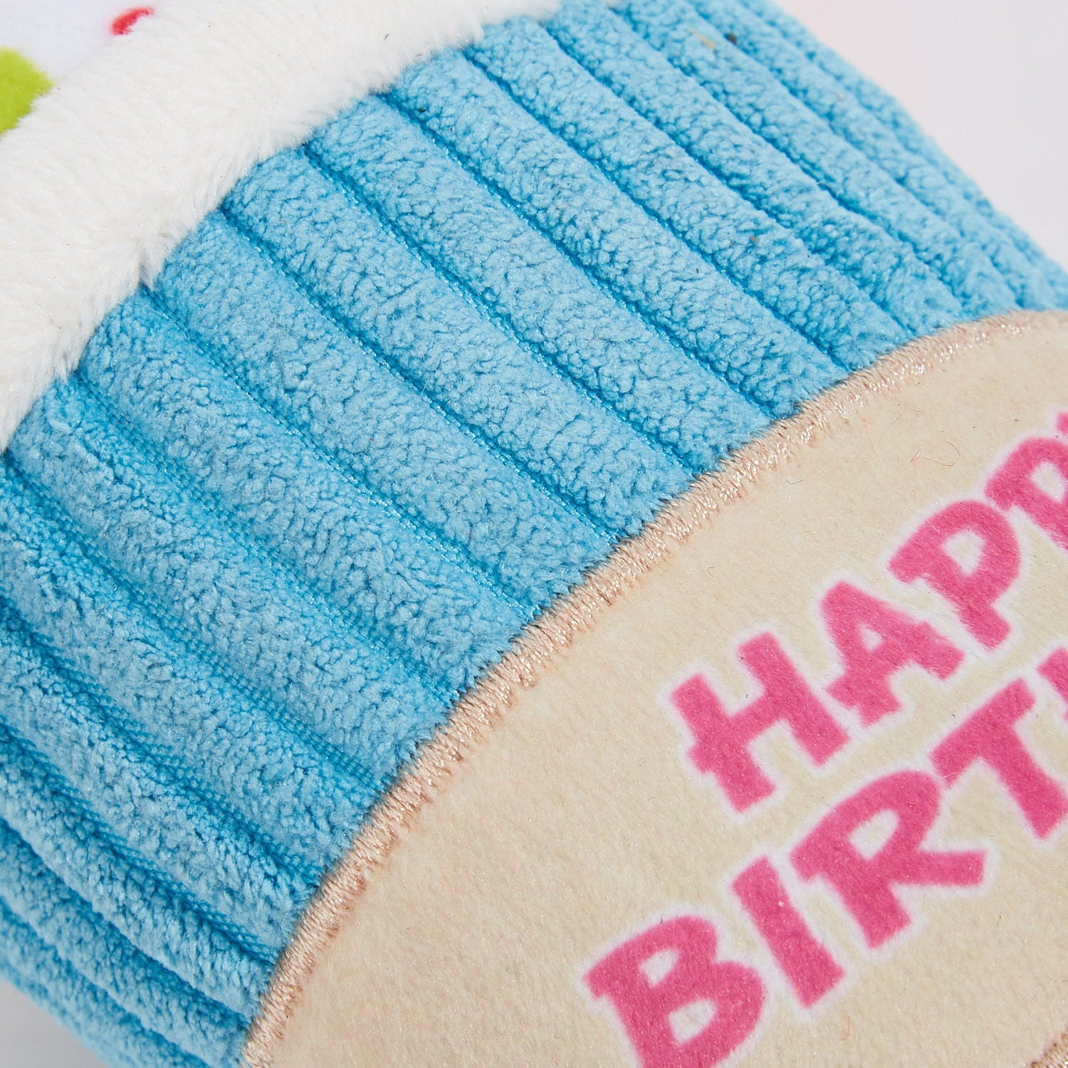 Close-up of a plush toy with 'Happy Birthday' text on a blue and beige background