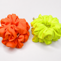 Two fabric hair scrunchies, one in bright orange and the other in neon yellow-green, displayed side-by-side on a clean white background.