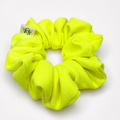 A bright neon yellow-green scrunchie made of plush fleece fabric, shown on a clean white background with a small white brand tag attached.