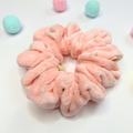 Pink fluffy scrunchie with pastel-colored balls on a light background